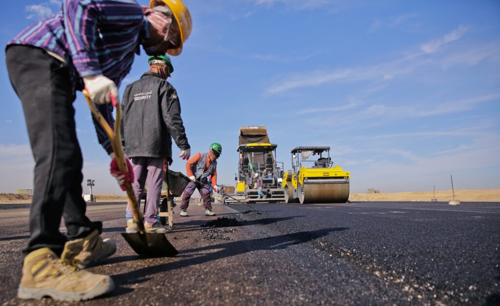 Road crew spreading asphalt with a roller behind them