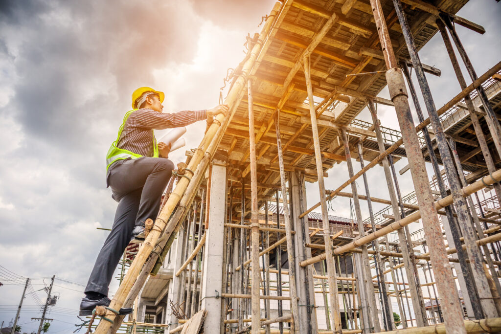 Construction worker climbing a cement structure.