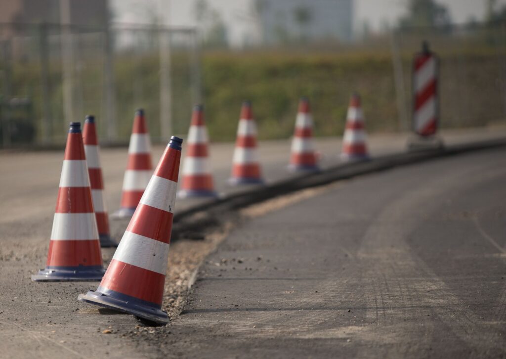 Row of red and white traffic cones along the edge of a road under construction
