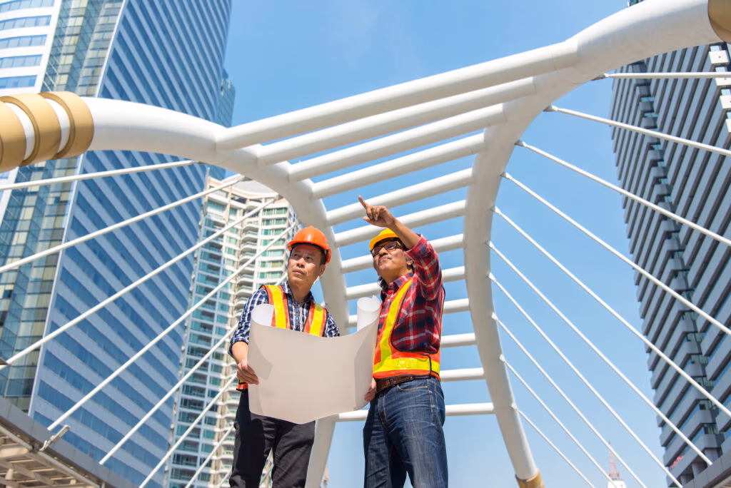 Two engineers reviewing plans on a pedestrian bridge