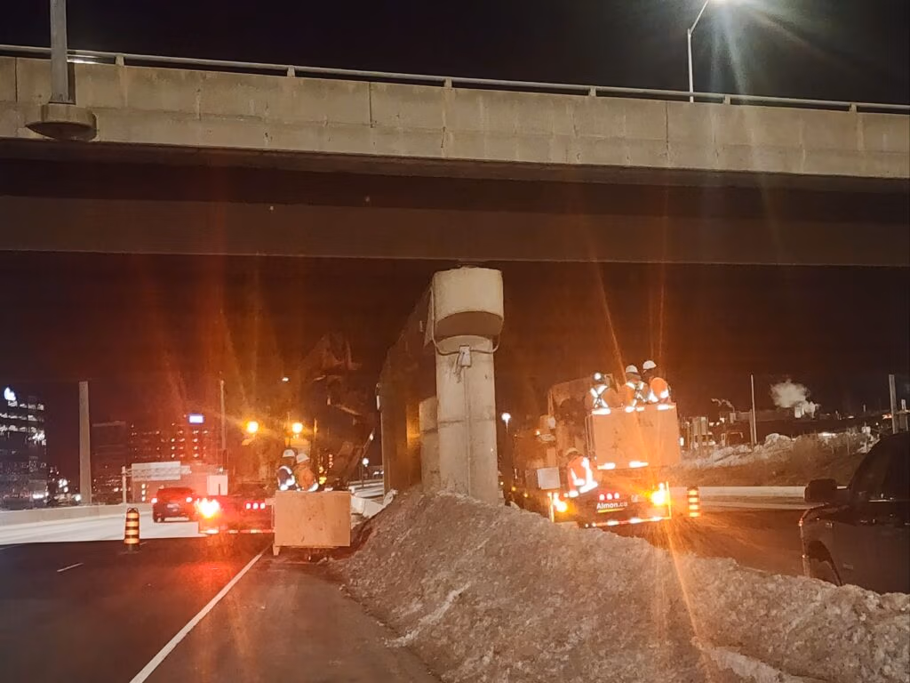Night-time inspection work beneath a highway overpass with work lights