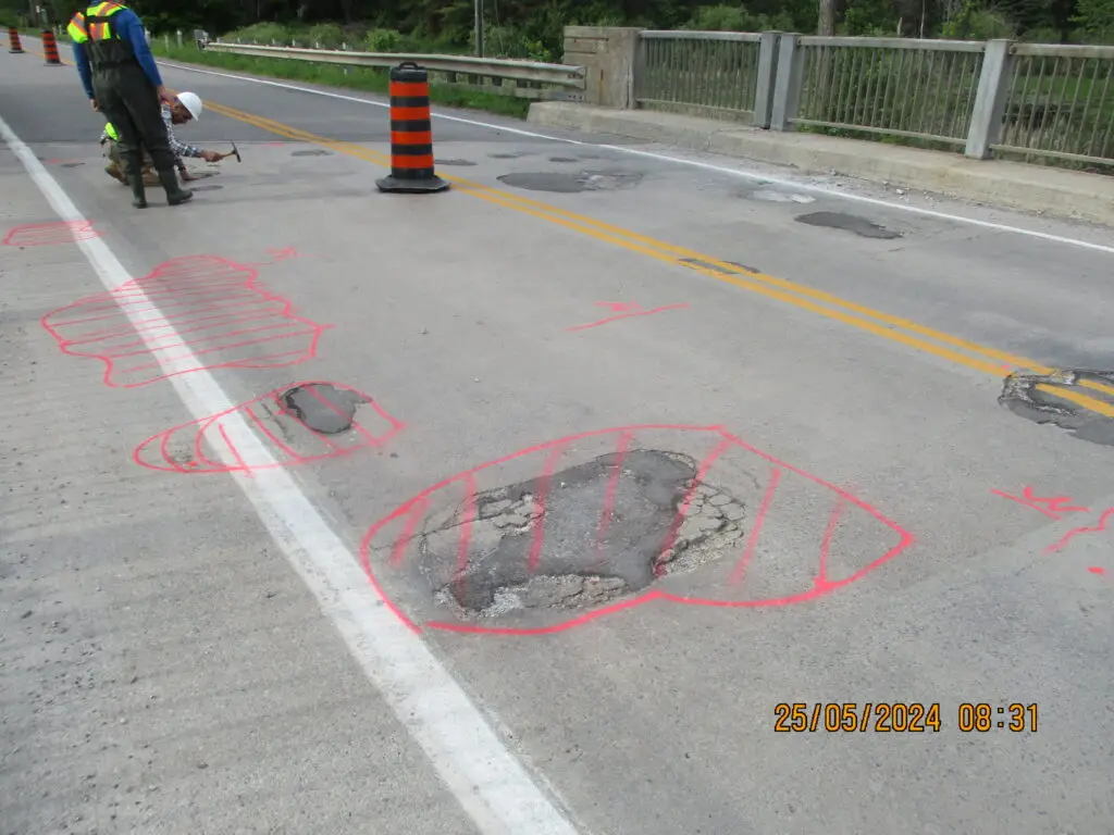 Road surface with pavement defects marked in paint for repair