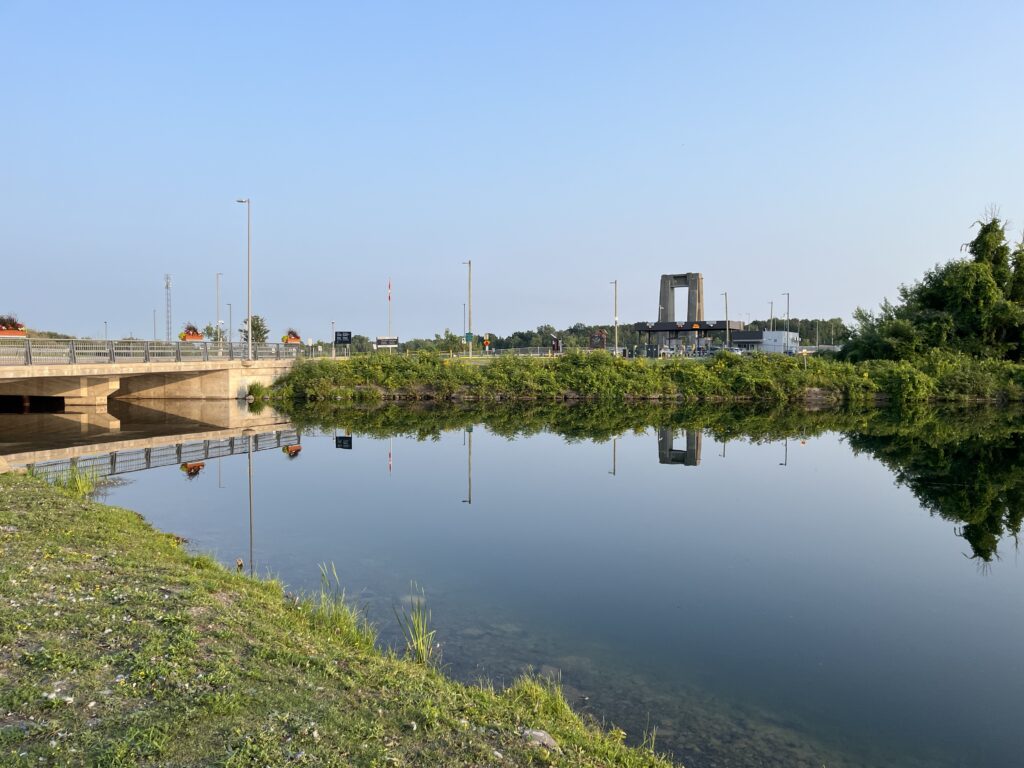 Calm creek reflecting the sky with a bridge in the distance