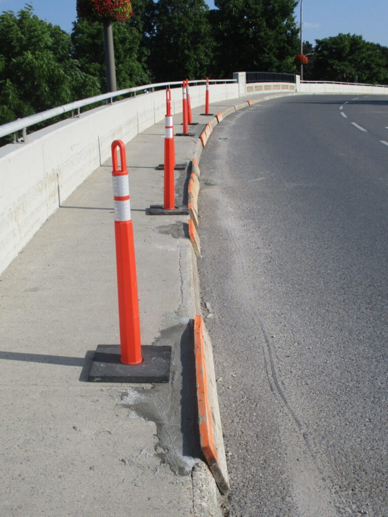 Bridge sidewalk lined with orange traffic delineators in Smiths Falls